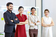 © Bangkok Click Studio - Group of millennial Asian young professional successful female businesswomen and Indian bearded male businessman in formal suit standing smiling in office