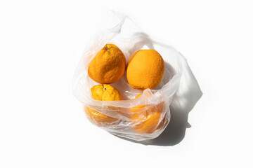 Sticker - Fresh ripe oranges in a transparent bag on a white background. Top view, flat lay