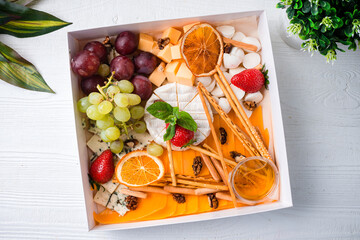 Wall Mural - cheese plate a box with a set of cheeses for food delivery with cheese, bread sticks