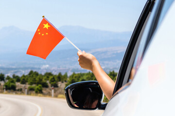 Wall Mural - Woman holding China flag from the open car window driving along the serpentine road in the mountains. Concept