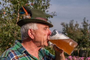 Wall Mural - Senior men with beer mugs with Bavarian beer in Tyrolean hats celebrating a beer festival in Germany. Happy old people during the October holiday in Munich