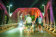 Group Of Men Riding The Pedicab (Cycle Rickshaw) On The Truong Tien Bridge At Night. Hue . Vietnam
