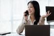 © kamiphotos - Beautiful Asian woman executives, business executives, marketing executives are talking on the phone with customers to contact the company for marketing. Marketing management concept.