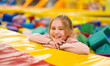 © Ievgen Skrypko - Pretty girl kid sitting in colorful cube trampoline at playground park and smiling. Beautiful female child happy during active entertaiments indoor