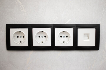 Set of four blackand white electric sockets outlet and ethernet port .