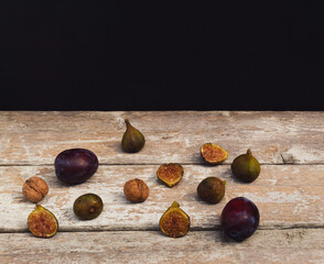 Wall Mural - Vintage style composition made of figs, plums and nuts on old wooden table. Dark background. Retro style food concept.