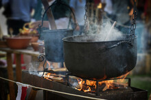 Large Iron Kettle Or Caldron With Steaming Stew Over Fire, Food For All On A Pristine Outdoor Feast, Selected Focus