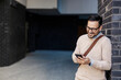 © Dusan Petkovic - A happy man leaning on the wall outside and typing messages on the phone.