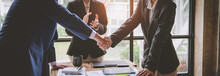 Business Team Shaking Hands And Clapping After A Business Deal Image Of Business Partners Handshaking Over Business Objects In The Office