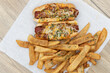 Overhead view of pair of chili cheese dog hotdogs loaded with melted cheese and served with pepper steak fries for a party appetite hunger meal