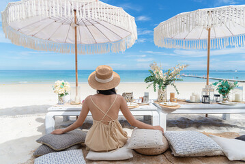 Sexy woman sit alone at table set for dinner on the beach