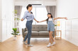 © anon - Happy asian family mother father and daughter dancing at home  in living room.