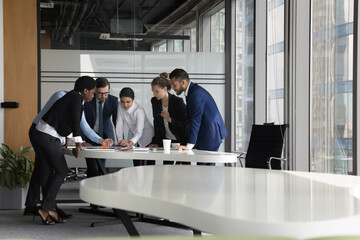 Sticker - Serious diverse business project group meeting at table in modern office, talking over paper reports, sharing ideas, decision, problem solving. Indian corporate coach teaching team of new employees