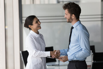 Poster - Two happy confident diverse business people shaking hands in office, smiling, laughing, talking. Customer giving handshake to manager, lawyer, ending meeting, negotiation, deal