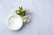 © Juver - Cosmetic facial body cream in glass jar and flowers on marble table. Minimalists still life with beauty products and white flowers on white background. Flat lay, top view, copy space