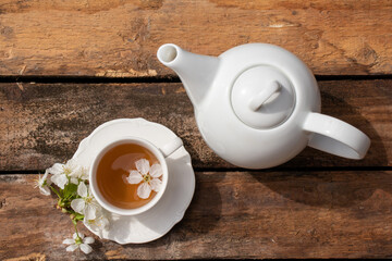 Cup of tea, teapot and white flowers on wooden table in garden outdoors. Relaxing slow life concept. Flat lay, top view