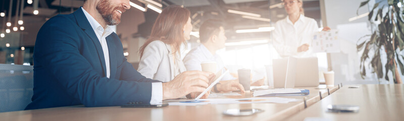 Wall Mural - creative smiling businessman working on a tablet during a meeting with a team. high quality photo