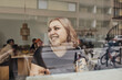 © Maskot - Happy female entrepreneur looking away while sitting in office seen through glass