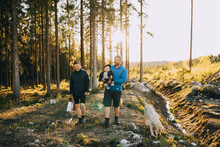 Parents With Son And Pet Dog Walking In Forest