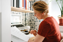 Businesswoman Examining Documents At Desk During Work From Home