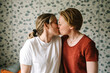© Maskot - Romantic lesbian couple kissing against wall at home