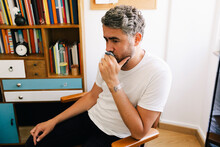 Contemplative Depressed Man Sitting On Chair In Therapy Office