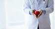 © kamiphotos - The doctor is holding a fake red heart, treating heart disease from a specialist and giving treatment on the spot. Concepts of medical treatment and specialists.