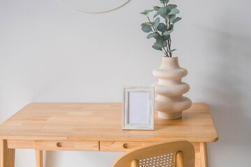 Wall Mural - Portrait white picture frame mockup on wooden table. Modern ceramic vase with eucalyptus. White wall background. Scandinavian interior. 