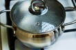 Boiling water in a in a covered stainless saucepan on a gas stove. Selective focus.