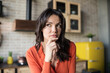 © Comeback Images - Portrait of beautiful brunette woman thinking or creating idea with her hand on chin in kitchen at home