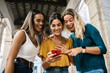 © Xavier Lorenzo - Young group of three multiracial female friends using smart phone mobile outdoor