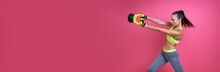 Confident Young Woman Exercising With Kettlebell Against Pink Background