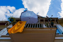 Umbrella And Dried Towel On The Balcony Of A Wooden House In Summer. Summer Vacation Concept.