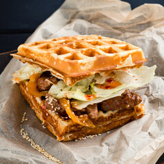 Canvas Print - Waffle sandwich with meat and vegetables on wooden table background