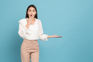 Young beautiful asian woman with smart casual cloth smiling and presenting copy space with surprise isolated on blue background