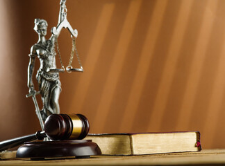 Wall Mural - On a dark beige background, a bronze figurine of Themis, the goddess of justice, a wooden judge's gavel and a book. Symbols of a fair trial, the rule of law.