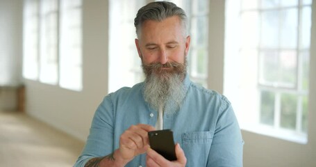 Trendy man using his phone indoors. Modern mature male using swipe feature on a latest networking or social media app. Casual guy interacting online or browsing the internet with modern technology