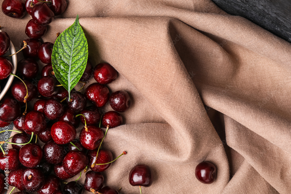 Heap of ripe cherries with water drops on fabric background
