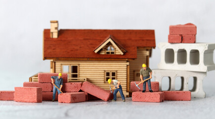 Miniature workers repairing houses. Miniature people and business concept.
