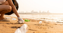 Volunteer Woman Picking Plastic Bottle Into Trash Plastic Bag Black For Cleaning The Beach, Female Clean Up Garbage At Sunset, Ecology Concept And World Environment Day, Save Earth Concept