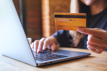 Canvas Print - Closeup image of a woman holding credit cards while using laptop computer for online payment