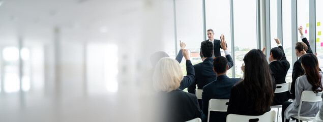 Group of business people meeting in a seminar conference widen view . Audience listening to instructor in employee education training session . Office worker community summit forum with speaker .