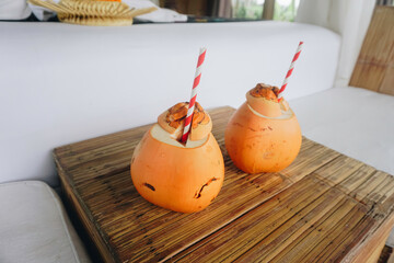 two coconut juices with paper straws placed on a wooden table