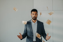 Serious Young Businessman Man Standing In Officethrowing Money Away, Inflation Concept.