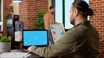 Poster - Startup employee analyzing business charts and greenscreen on laptop at office desk. Looking at report and isolated chroma key display with blank mockup copyspace background on screen.