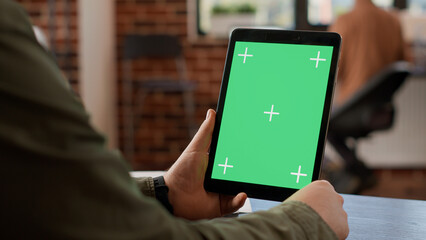 Poster - Startup employee looking at digital tablet with greenscreen, using gadget with isolated mockup copyspace and blank chroma key template. Device background and display. Close up.