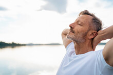 Mature Man Relaxing With Eyes Closed At Lake
