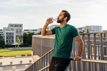 Bearded Man Drinking Water Leaning On Railing