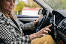 Smiling Businesswoman Using Phone Sitting In Car