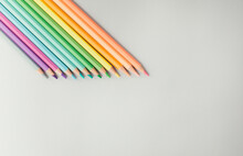 Studio Shot Of Row Of Colored Pencils Lying Against White Background
